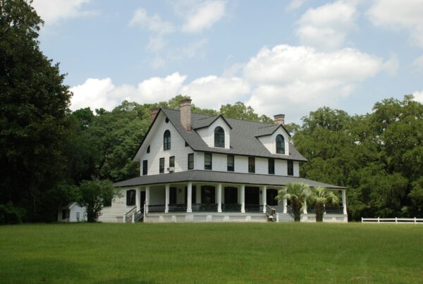 A beautiful custom home with a wrap-around porch and a large yard