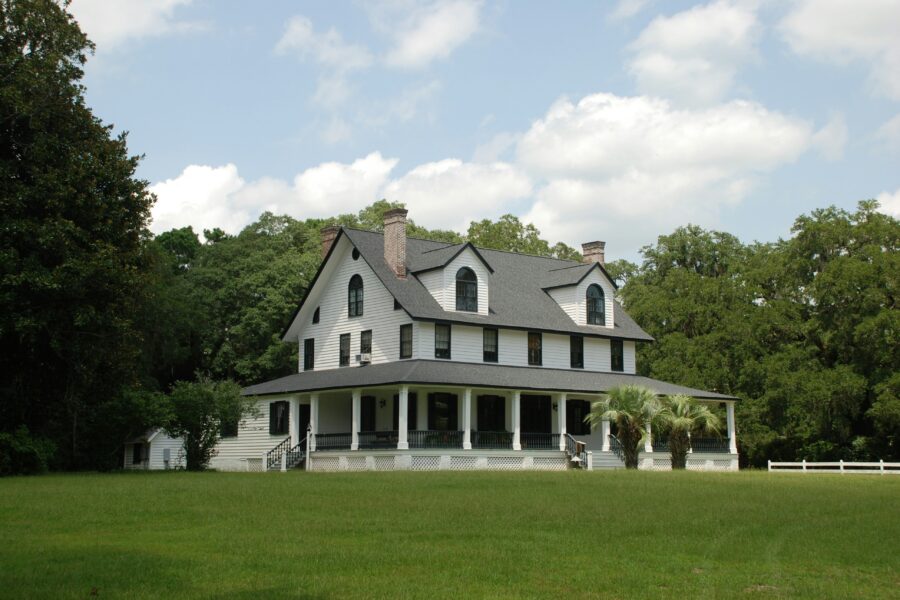 A beautiful custom home with a wrap-around porch and a large yard