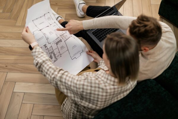 A couple sitting on the floor and looking over the designs for building their custom home.