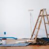 A ladder, painting supplies, and a drop cloth against a white backdrop as part of a remodeling project in Meridian, Idaho.