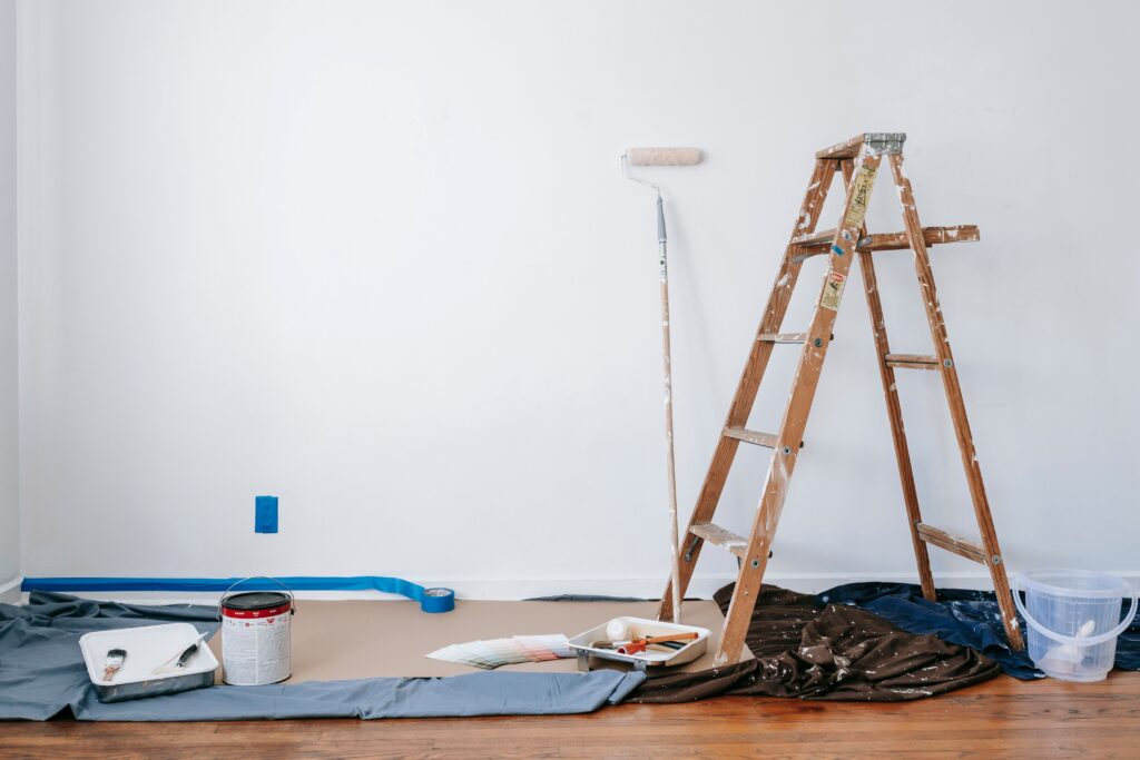 A ladder, painting supplies, and a drop cloth against a white backdrop as part of a remodeling project in Meridian, Idaho.