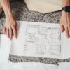 A homeowner's hands holding a custom home blueprint, showing how they are considering what features to invest in when building a home