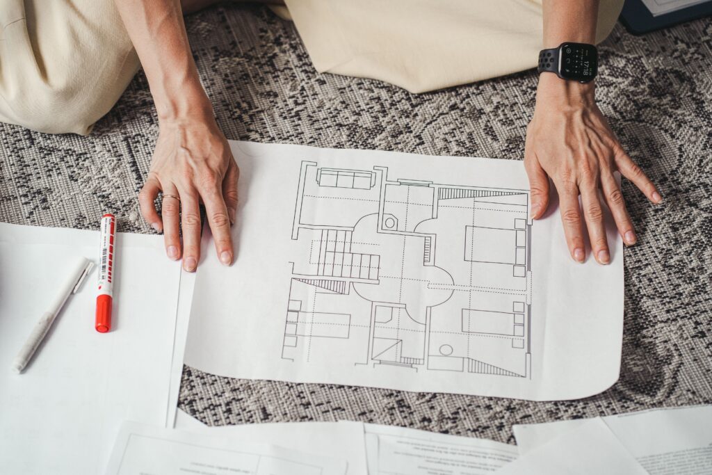 A homeowner's hands holding a custom home blueprint, showing how they are considering what features to invest in when building a home